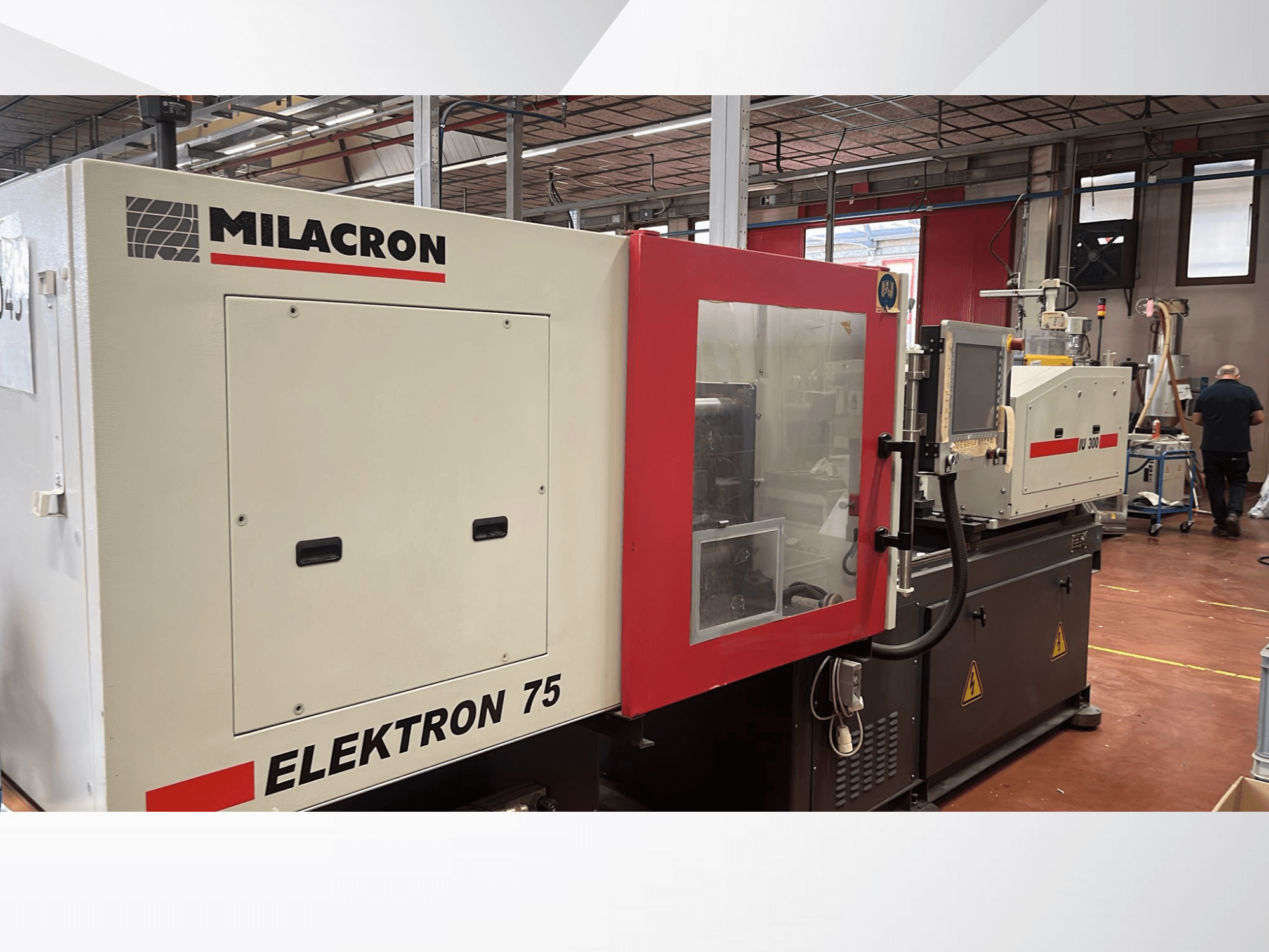 Термопластавтомат Milacron Elektron 75 в мастерской, вид сбоку, демонстрирующий панель управления и механические части.