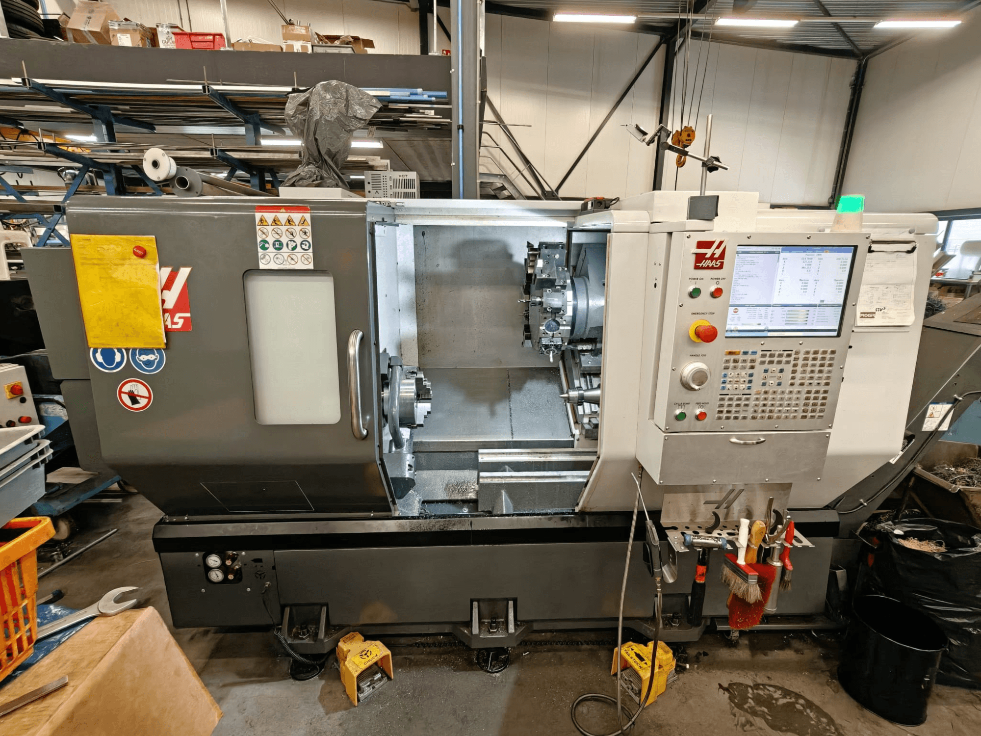 Горизонтальный токарный станок HAAS ST-25Y, вид спереди, демонстрирует панель управления, хранилище инструментов и оперативную настройку в мастерской.