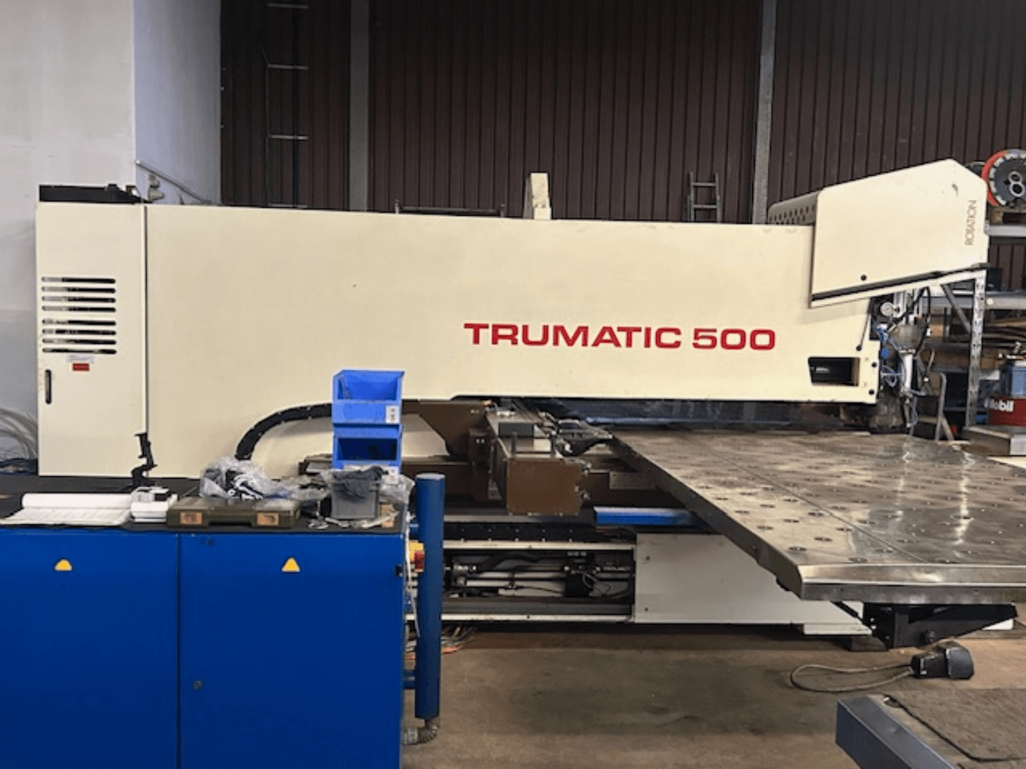 Пробивной станок с ЧПУ TRUMPF TRUMATIC 500, вид спереди, с панелью управления и большим рабочим столом с перфорированной поверхностью.