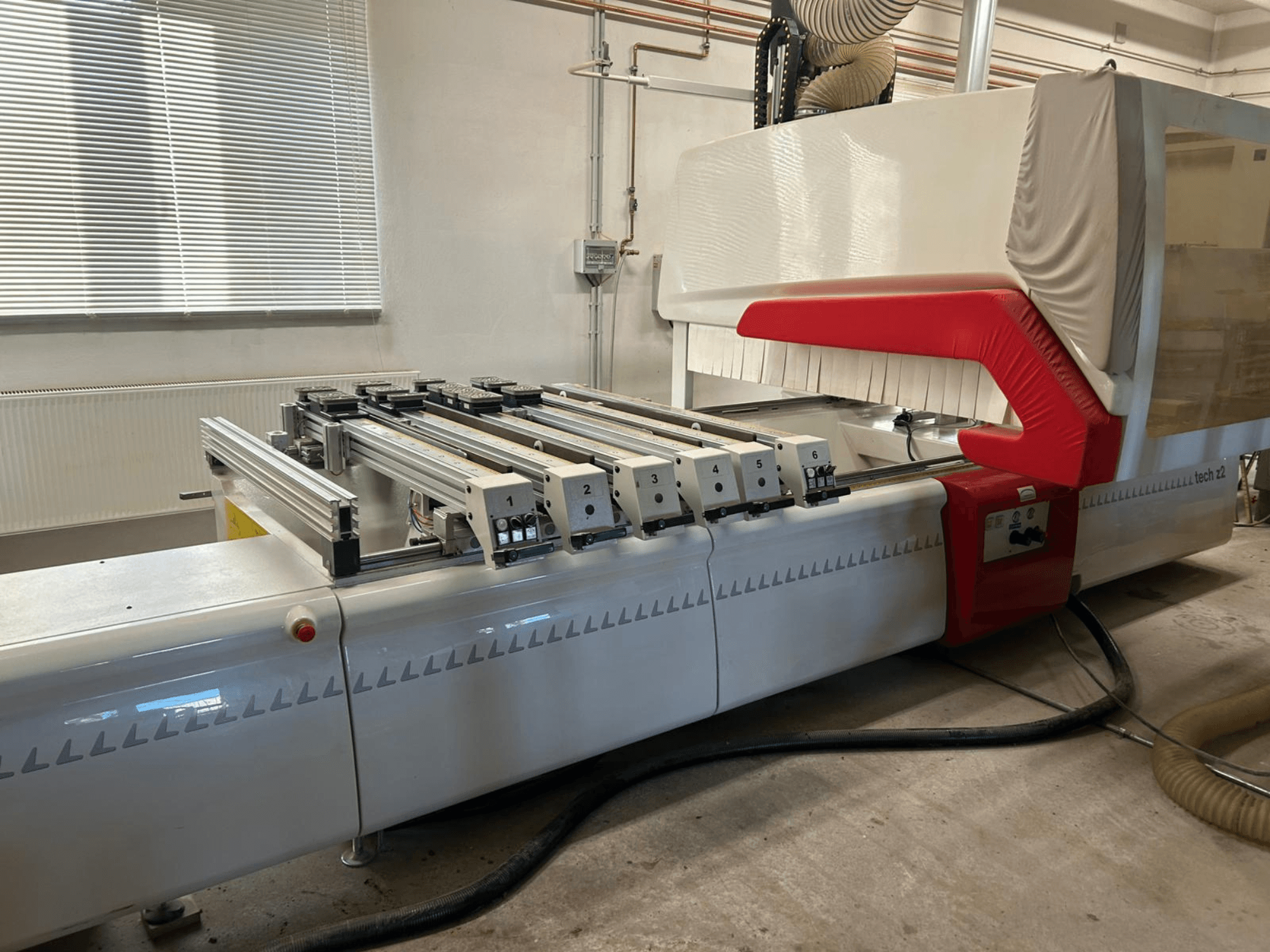 Сверлильный станок по дереву SCM TECH Z2-27-C, вид сбоку, с изображением панели управления и направляющих, с красными и белыми элементами дизайна.