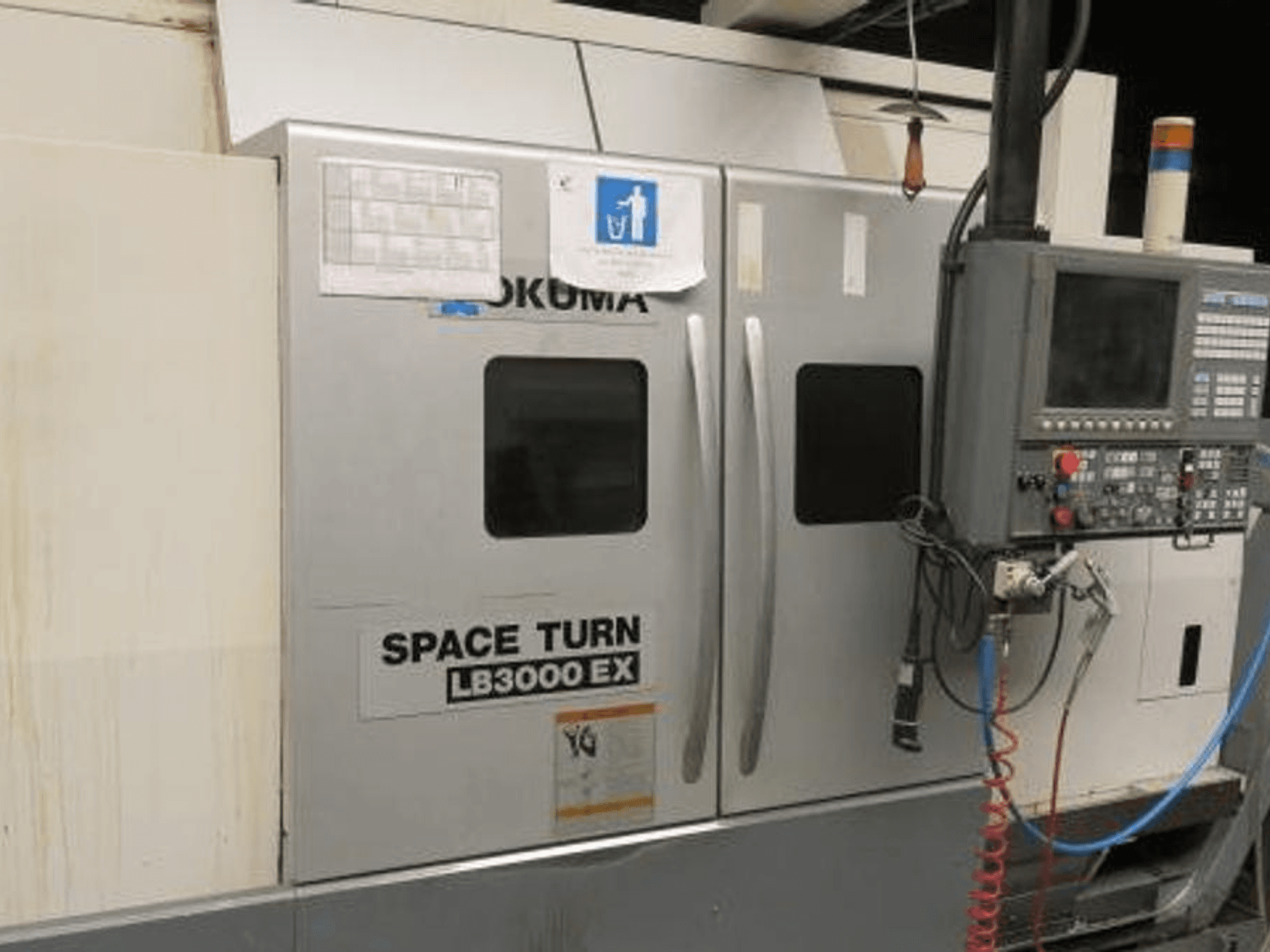 Токарный станок с ЧПУ Okuma Space Turn LB3000 EX, вид сбоку, панель управления, две дверцы и видимая проводка.