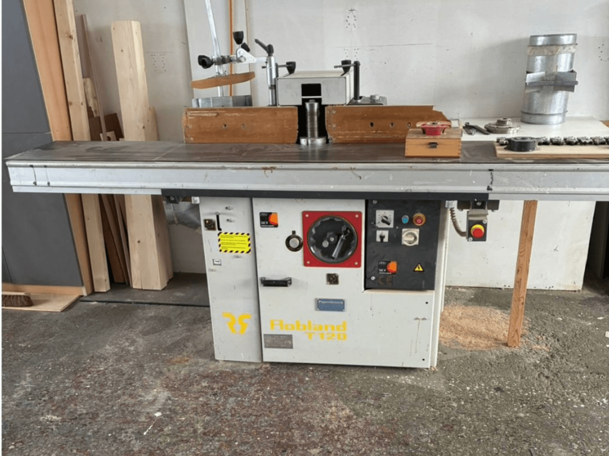 Настольный рубанок Hobbland T120, вид спереди, имеет серебристую поверхность, панель управления с кнопками и наклейки безопасности.